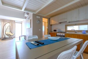 Une cuisine moderne avec des meubles en bois, un four à micro-ondes et un évier. On y trouve une table à manger avec des chaises et un set de table bleu.