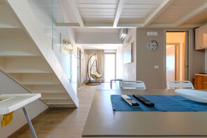 A modern hotel room with a staircase, a dining area with a table, chairs, and a remote control.
