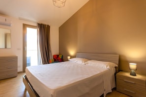 A bedroom with a bed, bedside table, lamp, and a chair.
