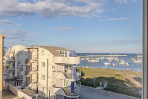 A multi-story building with balconies overlooking a marina with boats.