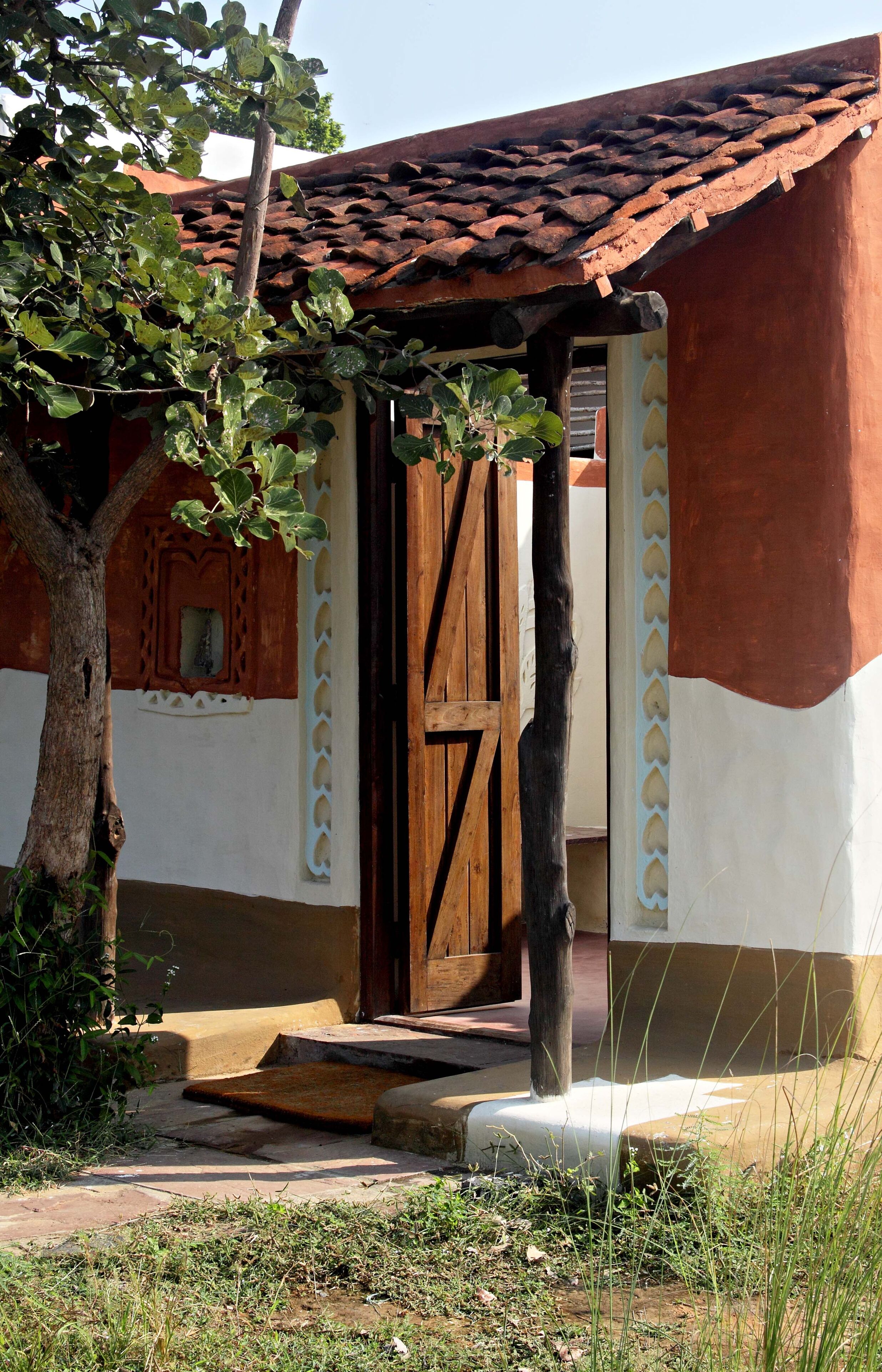 Un edificio rústico con puerta de madera, techo de tejas y un pequeño porche.
