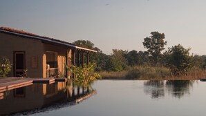 Ein Gebäude mit Pool, einer überdachten Terrasse und einer natürlichen Landschaft im Hintergrund.
