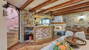 Un interior rústico con vigas de madera a la vista, una chimenea de piedra y una encimera de ladrillo curvada.