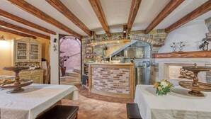 Un interior rústico con vigas de madera a la vista, una chimenea de ladrillo y una zona de bar con mostrador de ladrillo.