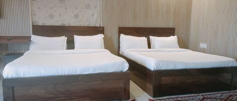 A hotel room with two beds, a patterned headboard, a red and white rug, and a wall-mounted air conditioner.