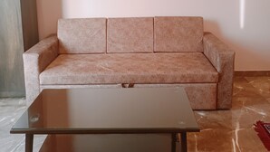 Una sala de estar con un sofá color beige, una mesa de centro de vidrio y un cuadro en la pared.