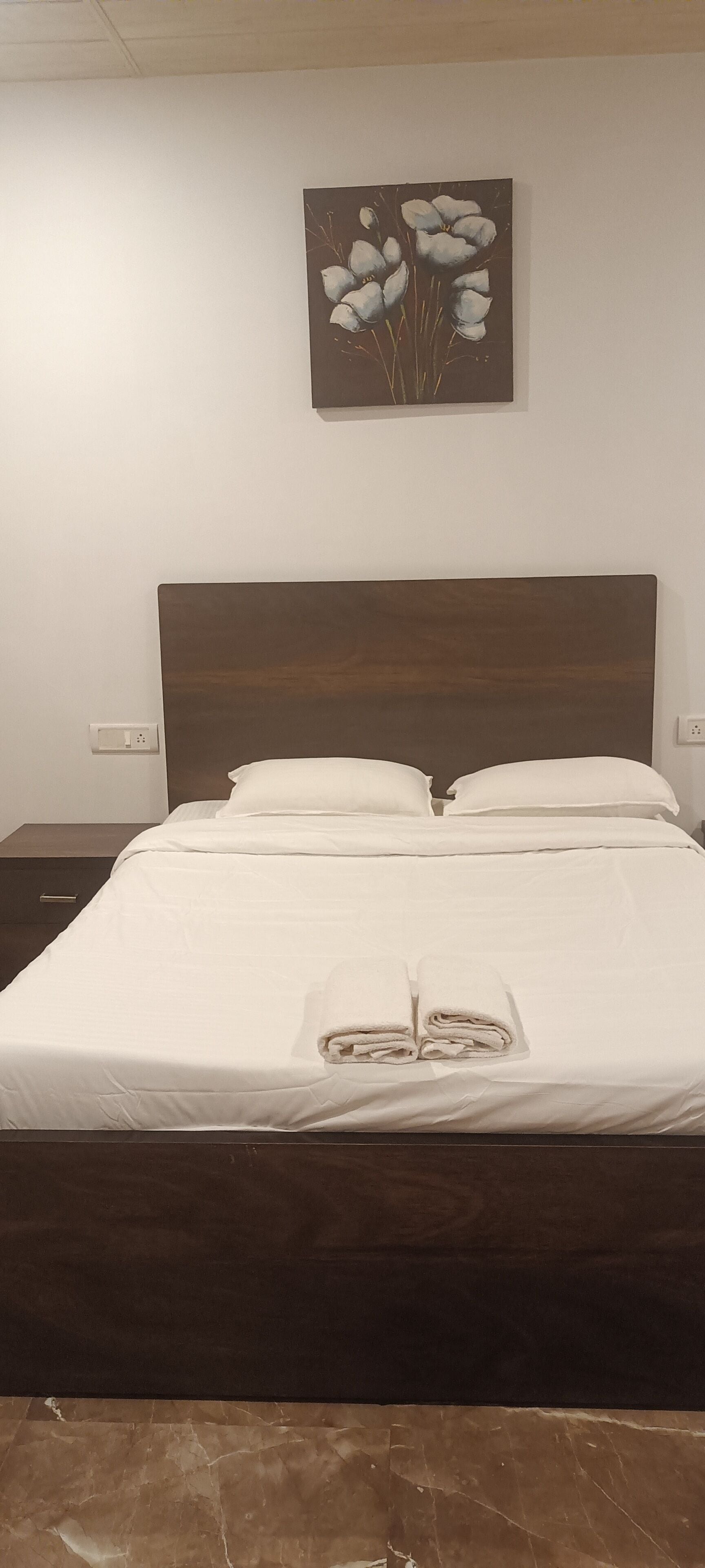 A neatly made bed with white linens and a folded towel on the bed.