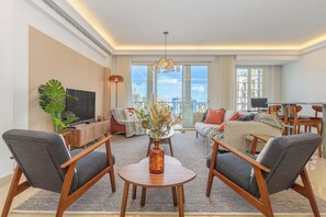 Una sala de estar moderna con un sofá, dos sillones, una mesa de centro y un televisor.