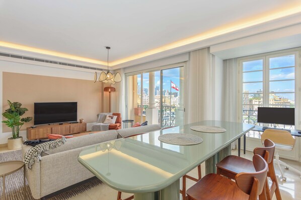 Una sala de estar moderna con sofá, televisión, mesa de comedor y sillas.