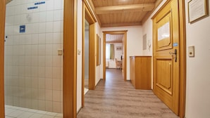 Un pasillo con puertas de madera, pared de azulejos y suelo de madera.