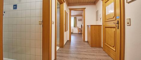 A hallway with wooden doors, a tiled wall, and a wooden floor.