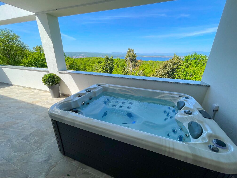 Un jacuzzi en un balcón con vistas a la vegetación y un paisaje distante.