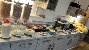 A buffet with various food items and condiments, including yogurt, cheese, and vegetables.