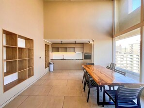 A modern kitchen with built-in appliances, a dining table with chairs, and a view through large windows. - Artistic Urban Apt Santa Elvira | Terrace & WiFi (Santiago)