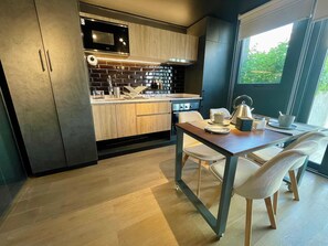 A modern kitchen with wooden cabinets, a black backsplash, and a dining area with a table and chairs.