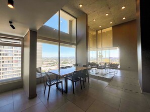A spacious room with large windows, a conference table, and chairs.