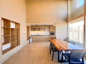 A modern kitchen with built-in appliances, a dining table with chairs, and a view through large windows. - Modern Studio - City Views, Fast Wifi & Parking (Santiago)