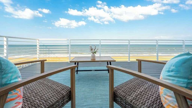 Une terrasse avec une table et des chaises, donnant sur un plan d’eau.