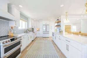A modern kitchen with white cabinetry, a central island, and a patterned rug.