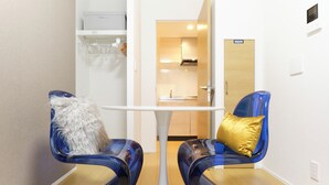 A modern room with two blue chairs, a white table, and a wooden door in the background.