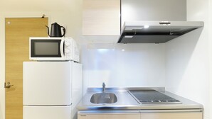 A compact kitchen with a microwave, stove, sink, and a refrigerator.