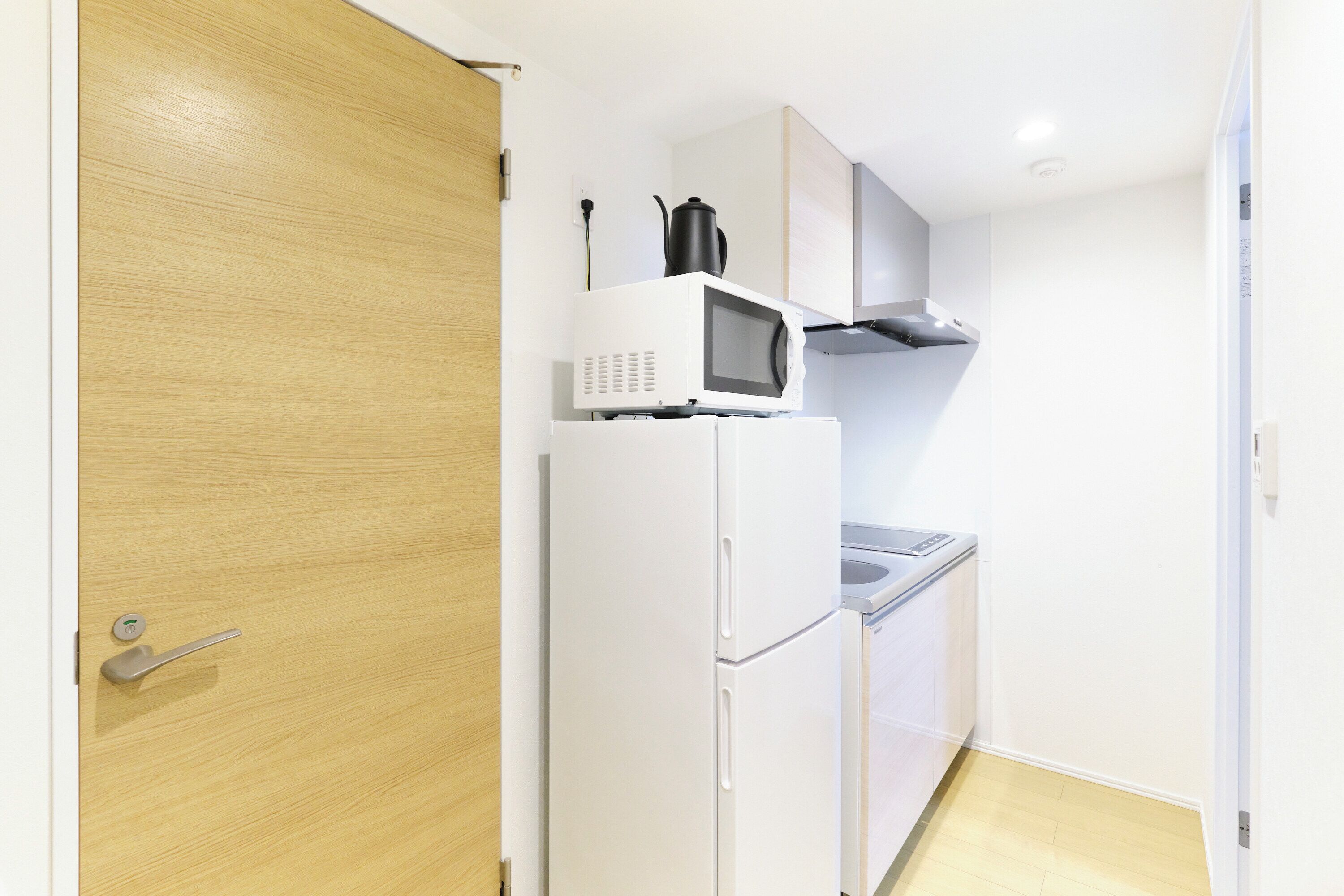 A compact kitchen with a microwave, a kettle, and a sink.