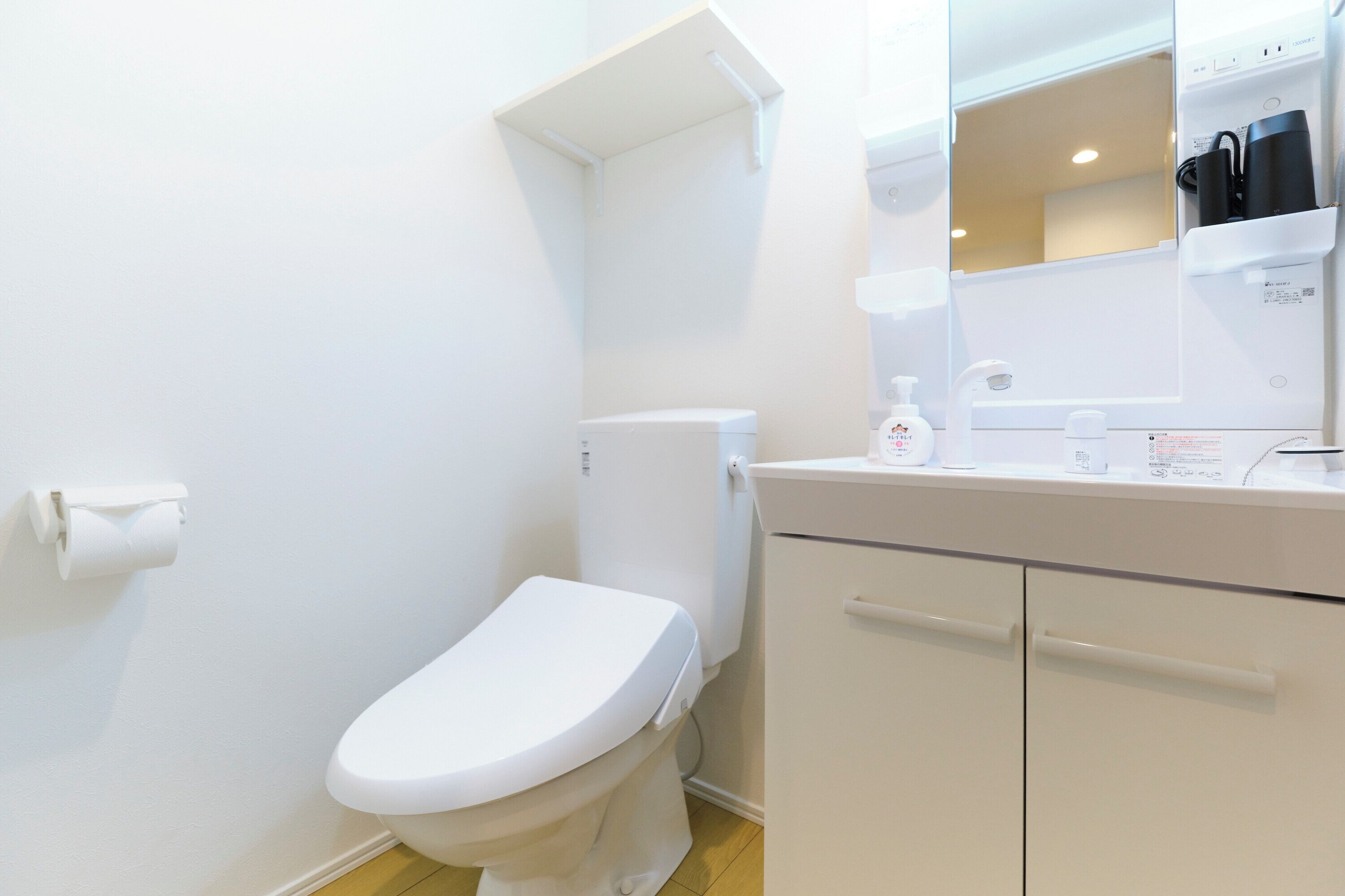 A modern bathroom with a white toilet, a sink with a mirror, and a cabinet.