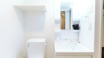 Een bad/douchecombinatie, een haardroger, pantoffels, handdoeken