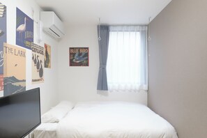 A bedroom with a bed, a flat-screen TV, and wall art. - Maison Ash Ikebukuro by Tranova (Tokyo)