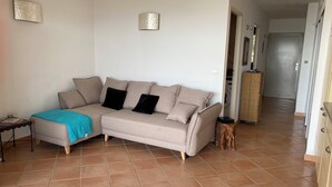 A living room with a beige sofa, two black cushions, a teal throw blanket, and a small side table. - Waterfront apartment 2/3 pers. Porto-Vecchio (Porto-Vecchio)