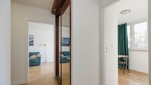 A modern apartment with a wooden floor, a blue sofa, a green chair, and a painting on the wall. - ShortStayPoland Waliców B171 (Warsaw)