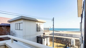 Zona residencial costera con un edificio blanco, un balcón y vista al mar.