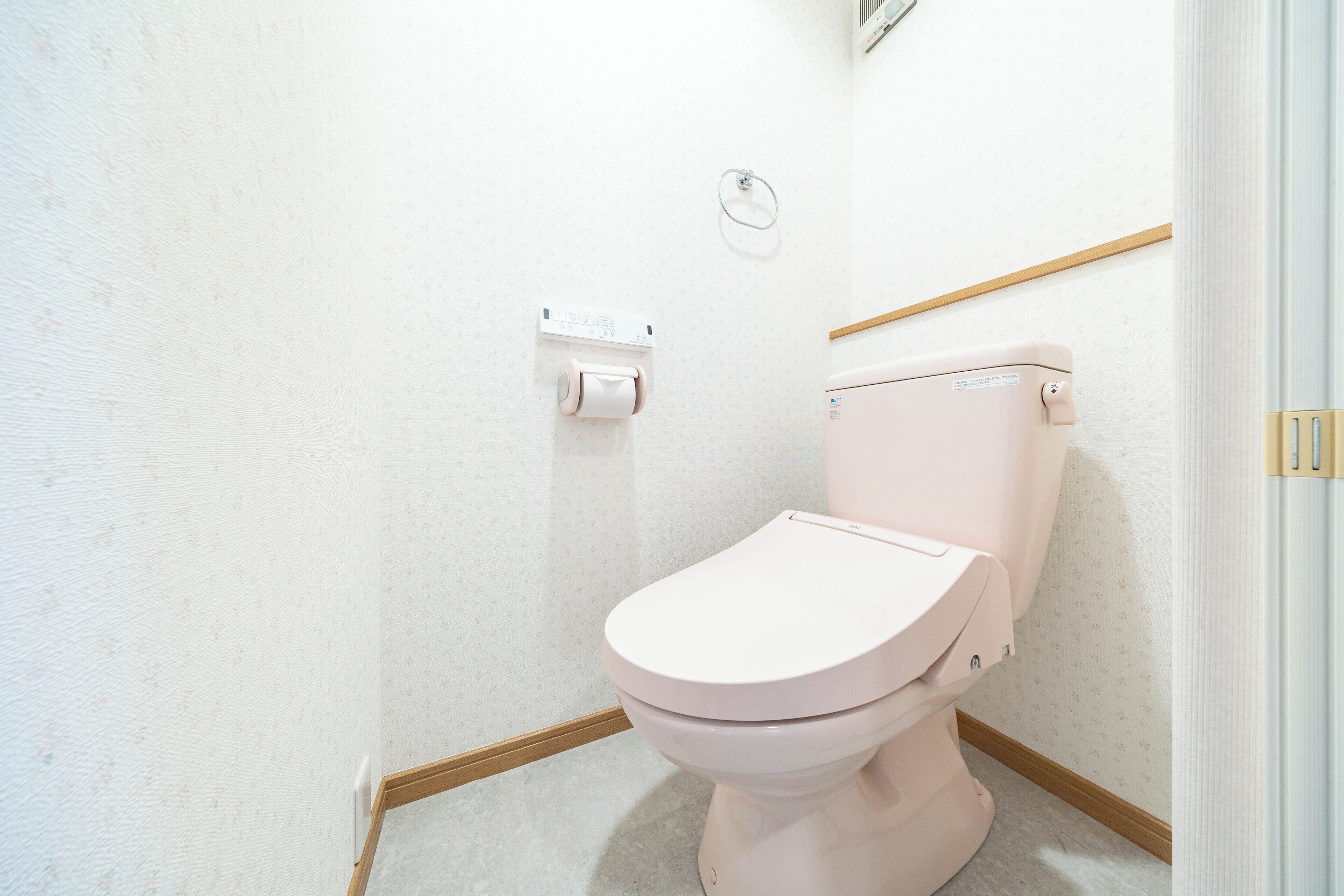 Une petite salle de bain propre, équipée de toilettes, d’un porte-rouleau de papier toilette et d’une poignée de chasse fixée au mur.