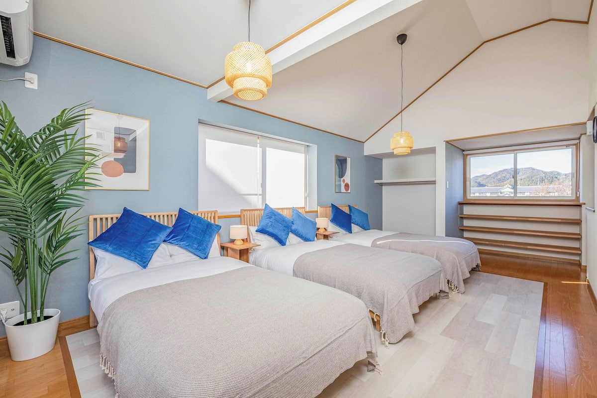 Un dormitorio moderno con dos camas, un ventanal grande y una escalera que sube a un nivel superior.