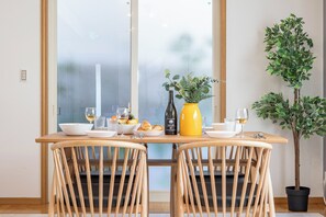 A dining table with chairs, a vase with flowers, and a bottle of wine. - Seaside House-THE BLUE- (Awaji)