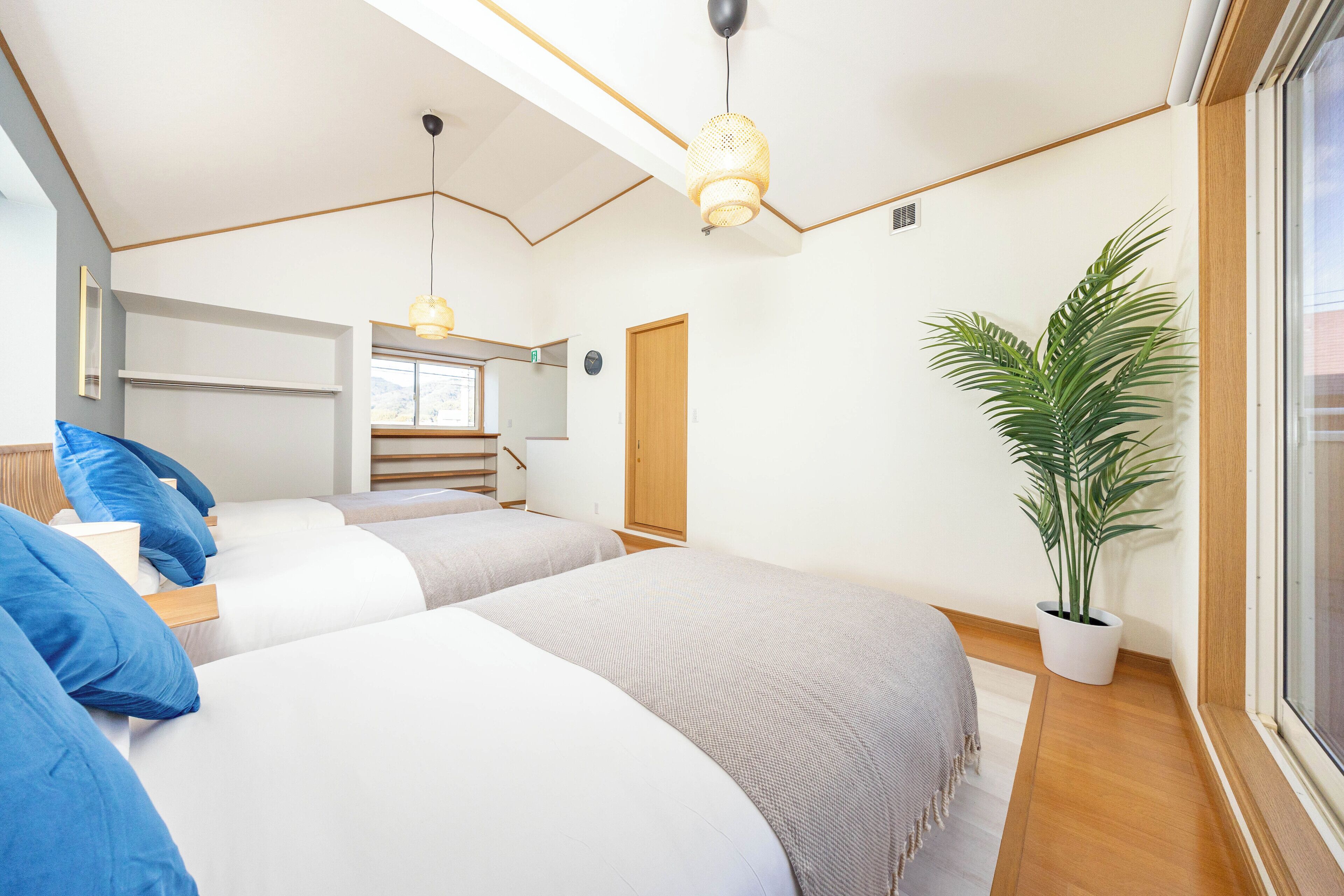 Ein Schlafzimmer mit zwei Betten, einer Zimmerpflanze und einem Fenster mit Blick.