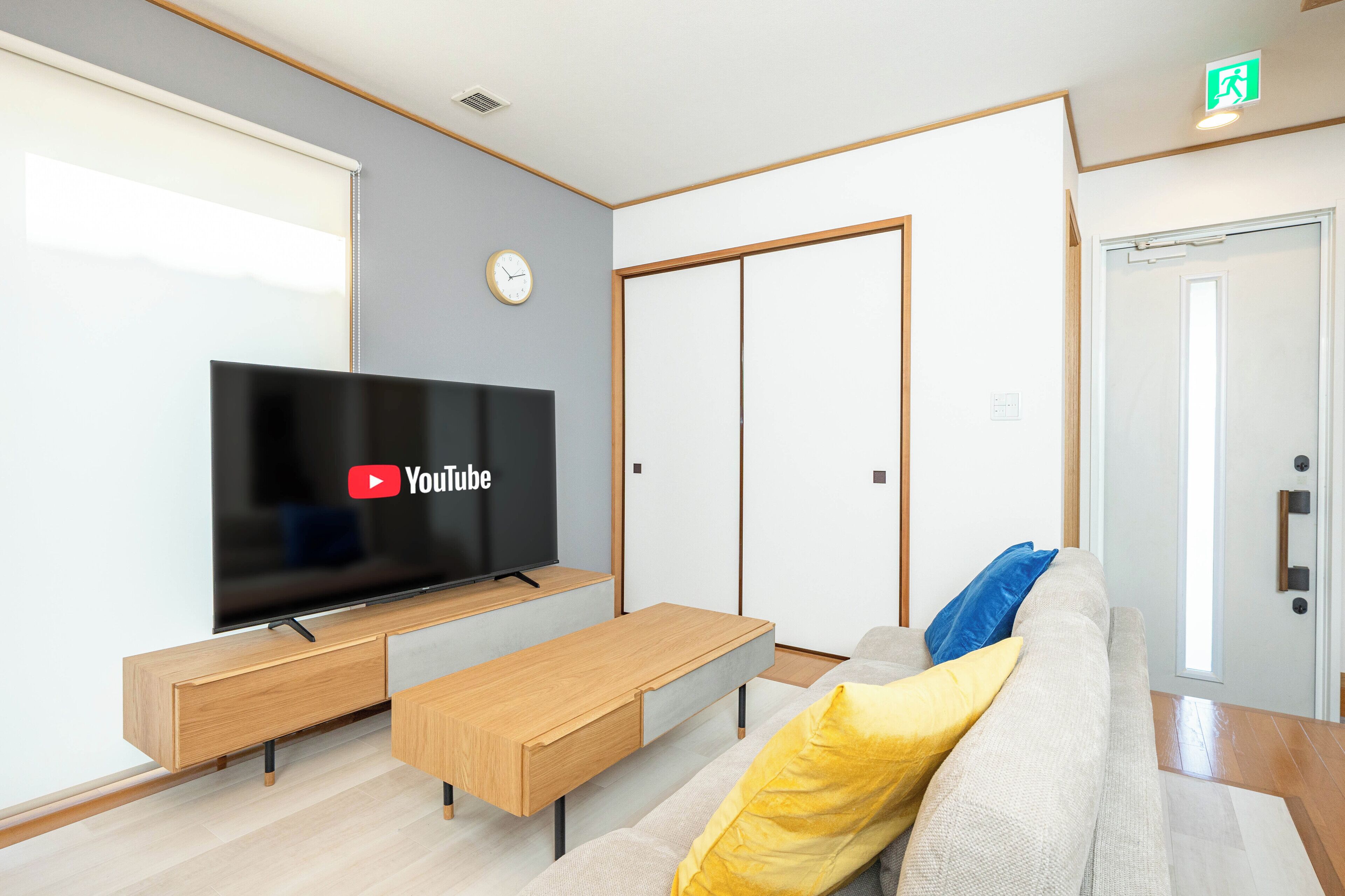 Un salon moderne doté d’un téléviseur à écran plat, de meubles en bois, d’un canapé avec des coussins et d’une armoire à portes coulissantes.