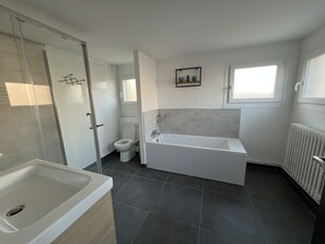 Un baño moderno con bañera, inodoro y zona de ducha.