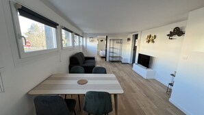 A modern, open-plan living space with a dining area, sofa, and TV. - Le Calais Wilson 4 : 2-4 Pers (Calais)