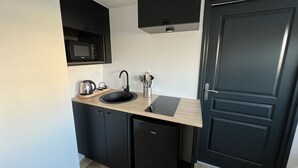 A compact kitchen with a black refrigerator, a microwave, a sink, and a coffee maker. - Le Calais Wilson 4 : 2-4 Pers (Calais)