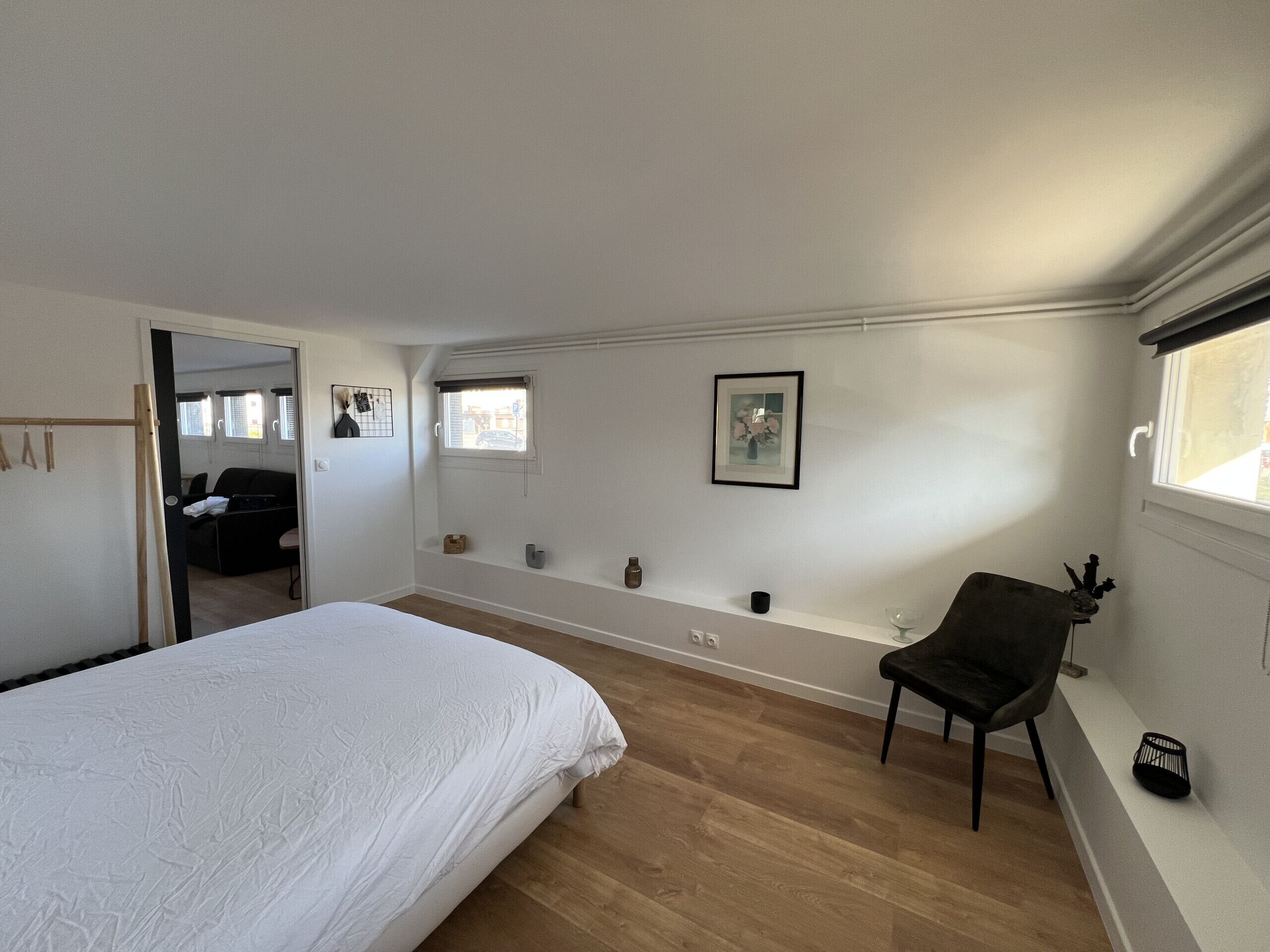 Ein Schlafzimmer mit einem großen Bett, einem Sessel, einem kleinen Tisch und einem Fenster.