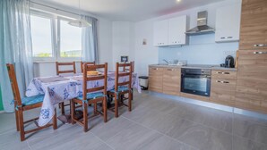 Une cuisine moderne avec des meubles en bois, un four encastré et un coin repas avec une table dressée pour quatre personnes.