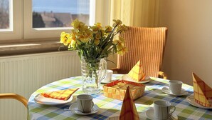 A table set for tea with a vase of yellow flowers, a wicker basket, and a striped chair. - "Welcome to the MADELEINE vacation apartment: pure relaxation and nature!" (Sipplingen)