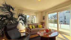 A living room with a sofa, a chair, a coffee table, and a large window. - "Welcome to the MADELEINE vacation apartment: pure relaxation and nature!" (Sipplingen)