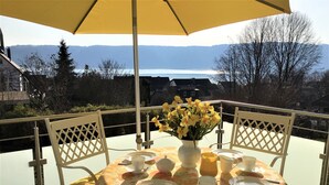 A table set outdoors with a yellow umbrella, surrounded by chairs, and a vase of yellow flowers. - "Welcome to the MADELEINE vacation apartment: pure relaxation and nature!" (Sipplingen)