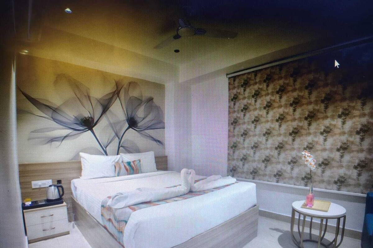 Une chambre à coucher moderne avec un grand lit, une petite table de chevet, un mur décoratif et un papier peint à motifs.