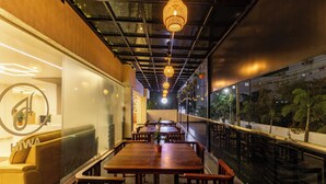 Un restaurante moderno con una larga mesa de madera y bancos, un sofá, y lámparas colgantes.