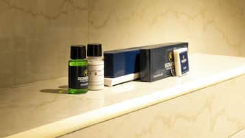 Una encimera de baño con un kit de afeitado, una botella de champú y un recipiente de crema hidratante.