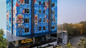 Un edificio con fachada azul adornada con motivos florales y el logotipo del Hotel Boutique HIVA.
