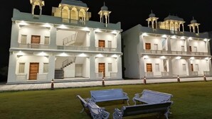 A large, multi-story building with balconies and a staircase. - Roop Garh Palace (Jamwa Ramgarh)